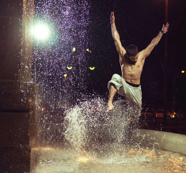 筋肉男の噴水でジャンプ ストック写真