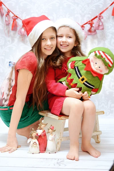Duas irmãs sorridentes usando chapéus de Papai Noel Imagens Royalty-Free