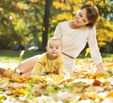 Yapraklarda bebekle yatan anne