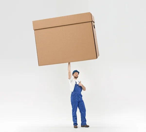 Little builder holding a huge box — Stock Photo, Image