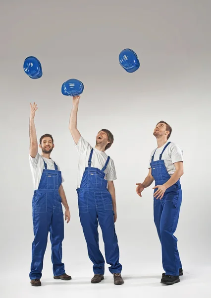 Young tired builders throwing helmets — Stock Photo, Image