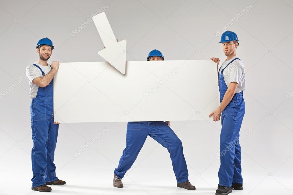 Three handsome builders holding a banner