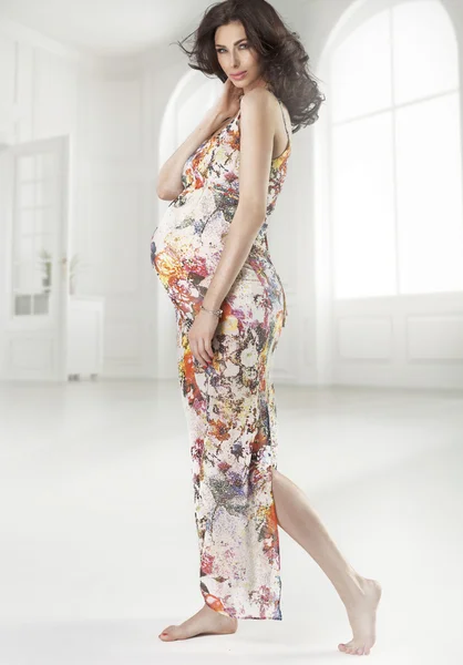 Brunetka w ciąży kobieta ubrana kwitnące sukienka — Zdjęcie stockowe