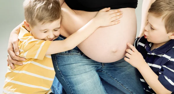 Filhinhos acariciando a barriga da mãe grávida — Fotografia de Stock