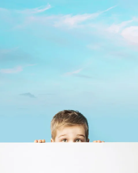 Fina porträtt av en liten pojke som gömmer sig bakom en styrelse — Stockfoto