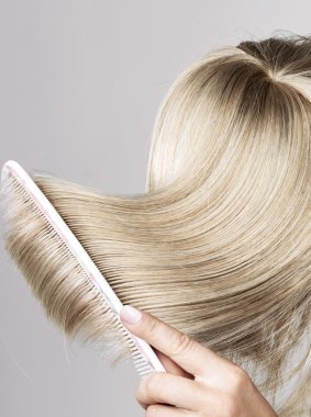 Blond hairpiece brushed by a woman clipart