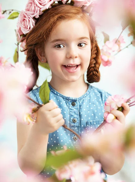 Fröhliches kleines Mädchen mit einem Ast in der Hand — Stockfoto