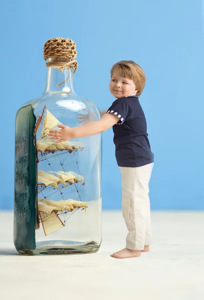 Rapaz bonito segurando uma garrafa de brinquedo — Fotografia de Stock