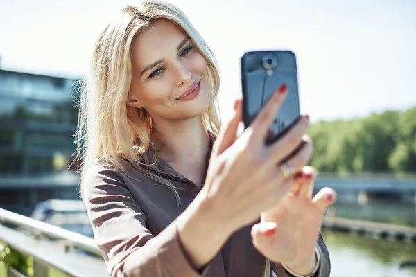 Retrato de uma mulher loira tirando uma selfie — Fotografia de Stock