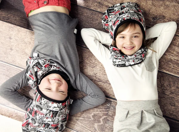 Frères et sœurs joyeux couchés sur le sol en bois — Photo