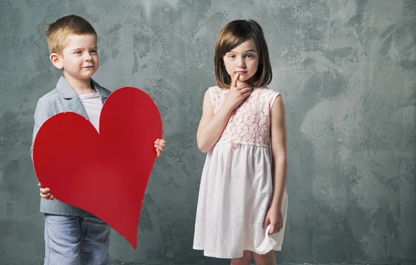 Niedlicher kleiner Junge, der seiner Schwester ein Herz schenkt — Stockfoto