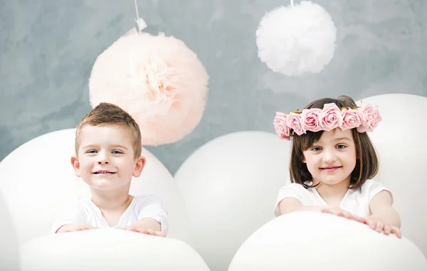Adorables niños jugando globos blancos — Foto de Stock