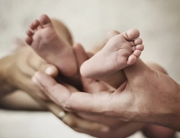 Conceptual picture of parents golding a baby's feet — Stock Photo, Image