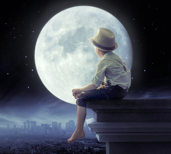 Маленький мальчик смотрит на город в ночи
