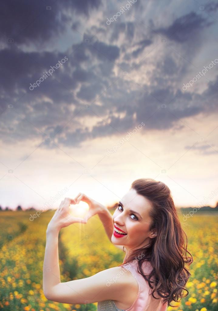 cheerful young woman making a heart sign