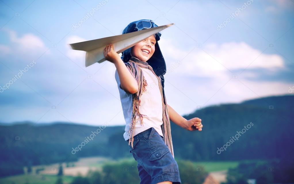 Cheerful little boy playing paper plane