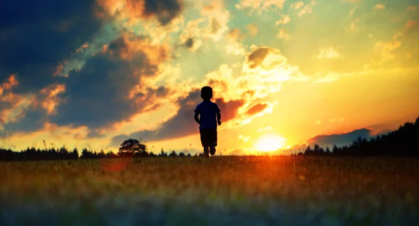 Cheerful boy running towards the sunset — Stock Photo, Image