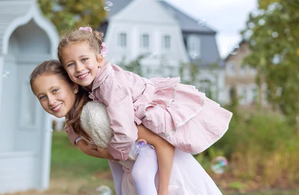 दो प्यारी बहनें शरद ऋतु उद्यान का आनंद ले रही हैं स्टॉक इमेज