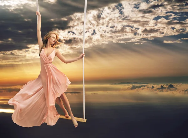 Attractive young lady on a swing above the sea — Stock Photo, Image
