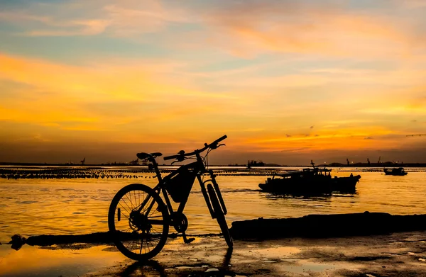 Silhueta de bicicleta no molhe com céu por do sol e fundo do mar — Fotografia de Stock