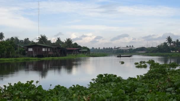 Langhalet båt ved Tha Chin-elva med hus ved elven – stockvideo