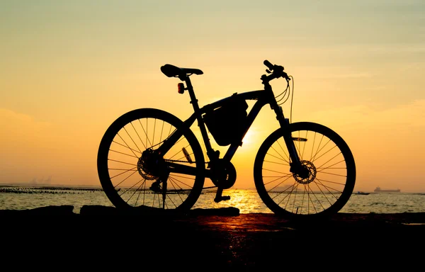 Silhouette of mountain bike at sea with sunset sky background — Stock Photo, Image