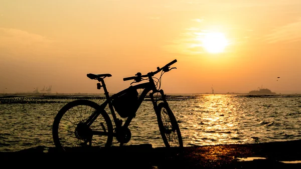 Silhuett av mountainbike till sjöss med solnedgång himmel bakgrund — Stockfoto
