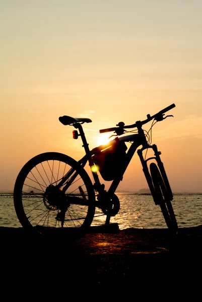 Silhueta de bicicleta de montanha no mar com fundo céu por do sol — Fotografia de Stock