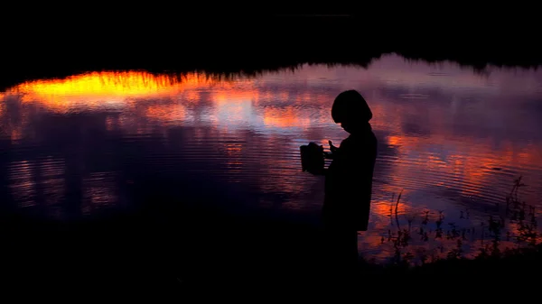 Силуэт ребенка у болота с отражением закатного неба — стоковое фото