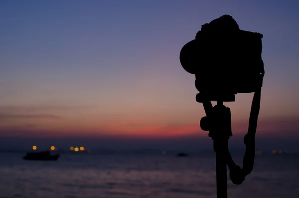 Silhouette einer Digitalkamera auf Stativ mit Sonnenuntergang am Meer — Stockfoto