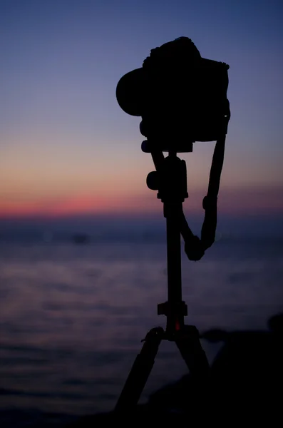 Silhouette einer Digitalkamera auf Stativ mit Sonnenuntergang am Meer — Stockfoto