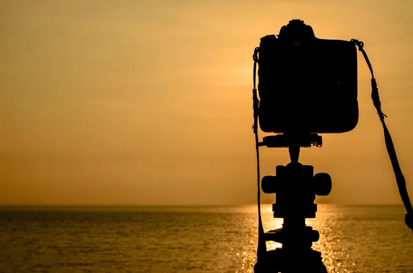 Silhouette einer DSLR-Kamera mit Meer bei Sonnenaufgang — Stockfoto