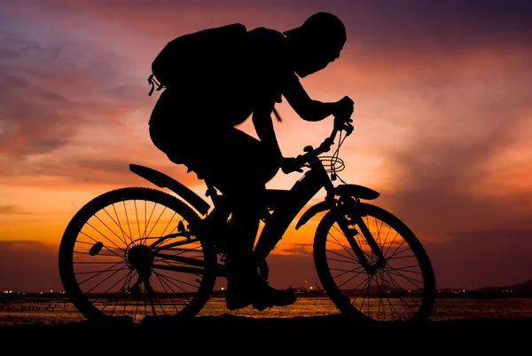 Silhouette von Backpacker fahren Mountainbike auf Brücke am Meer — Stockfoto