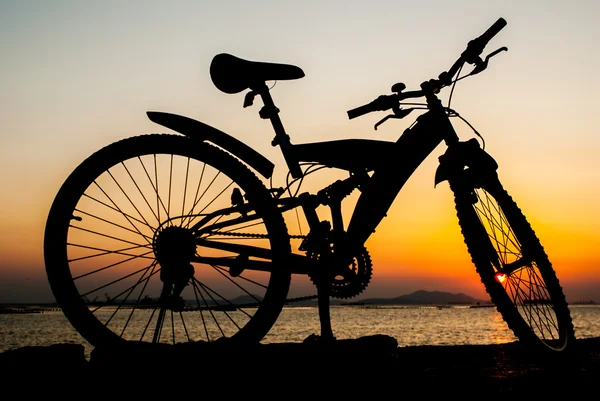 太陽と海の横にある桟橋に駐車場、マウンテン バイクのシルエット — ストック写真