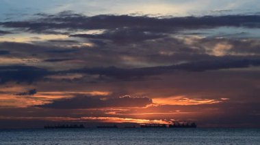 Kargo gemileri siluetleri ile denizde gün batımı gökyüzü