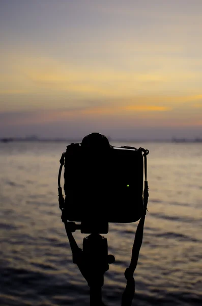Silueta de cámara réflex digital en el mar con puesta de sol — Foto de Stock