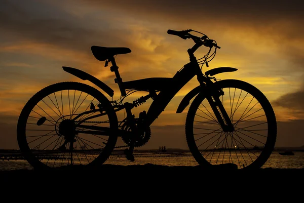 Silhueta de bicicleta de montanha com céu pôr do sol ao lado do mar — Fotografia de Stock