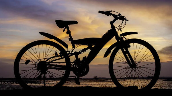 Silhueta de bicicleta de montanha com céu pôr do sol ao lado do mar — Fotografia de Stock