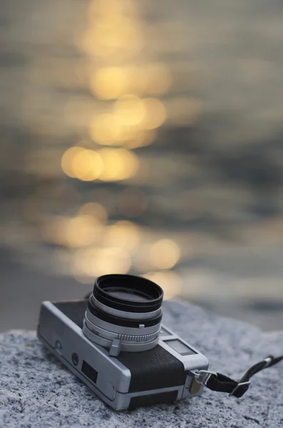 Relájese con la cámara vintage al lado del mar con puesta de sol bokeh reflejado — Foto de Stock