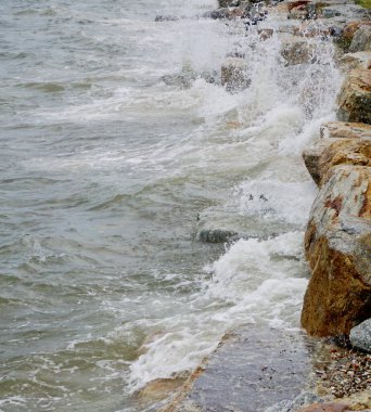 Dalgalar sahildeki kayalara çarpar, yakın çekim.