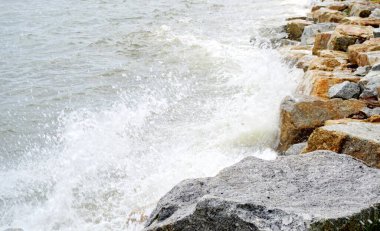 Dalgalar sahildeki kayalara çarpar, yakın çekim.