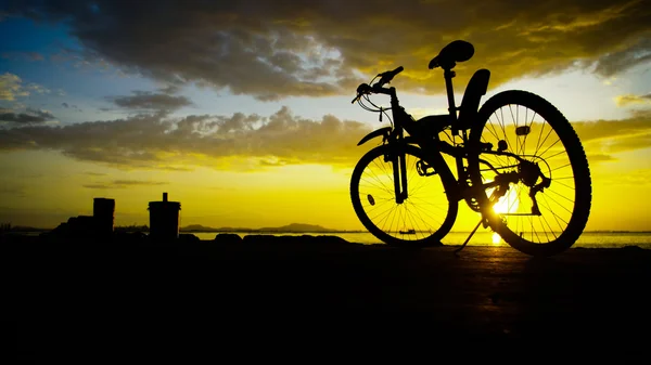 Silhuett av mountainbike med solnedgång himlen vid havet — Stockfoto