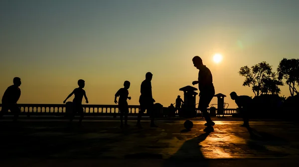 Silueta de hombre y niño jugar al fútbol con el cielo puesta de sol —  Fotos de Stock