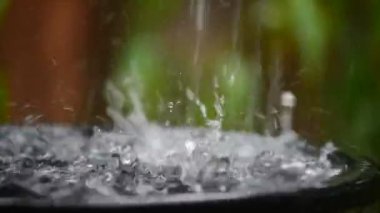 Yeşil bahçe arka plana sahip siyah havzasında dökülen yağmur suyu