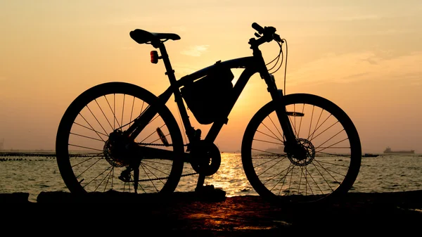 Silhueta de bicicleta de montanha no mar com céu por do sol — Fotografia de Stock