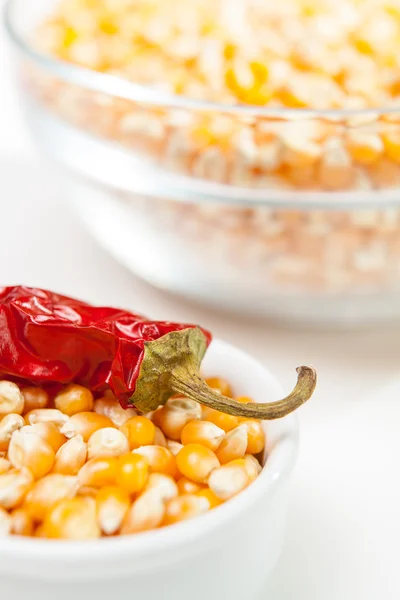 Chili peppar i en skål med majs korn — Stockfoto