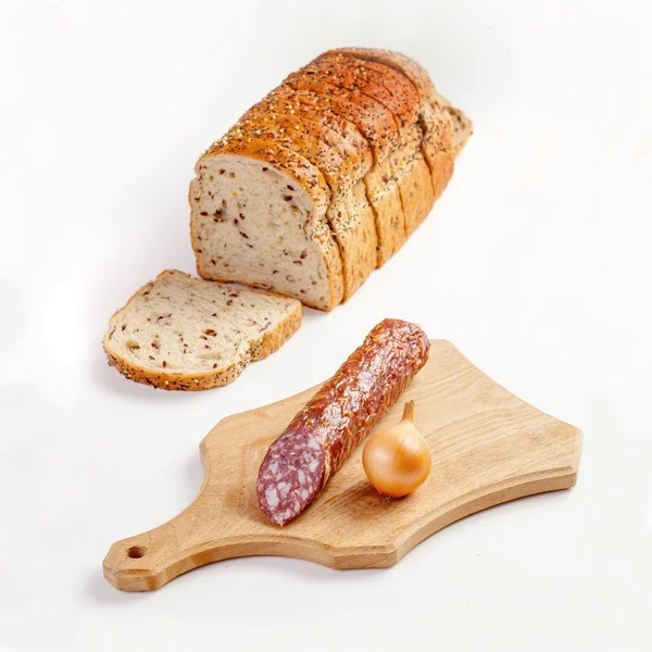 Salami, lök på skärbräda och bröd — Stockfoto