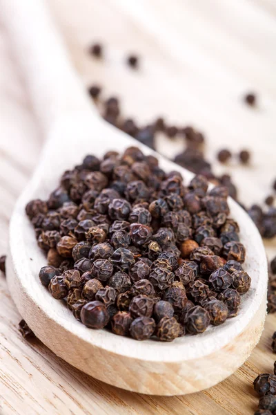 Black pepper on wooden spoon close up — Stock Photo, Image