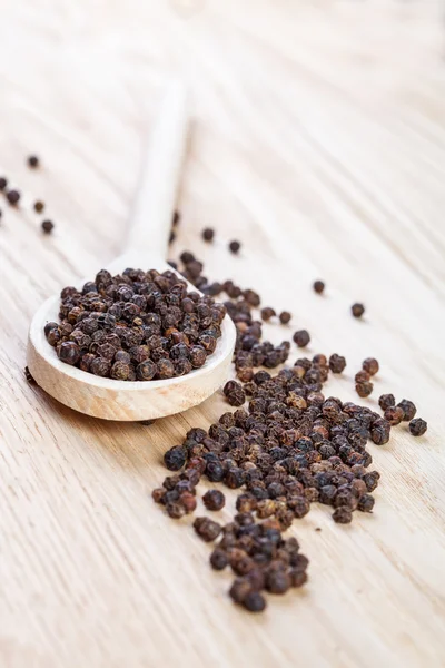 Black pepper on wooden spoon close up — Stock Photo, Image