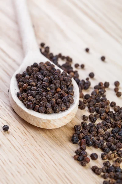 Black pepper on wooden spoon close up — Stock Photo, Image